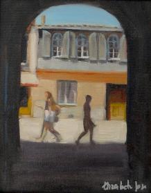 A bright street scene through an archway with walking figures