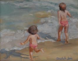2 little girls in matching swimsuits play at the beach