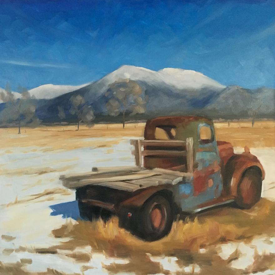 old truck in a paddock with snow mountains